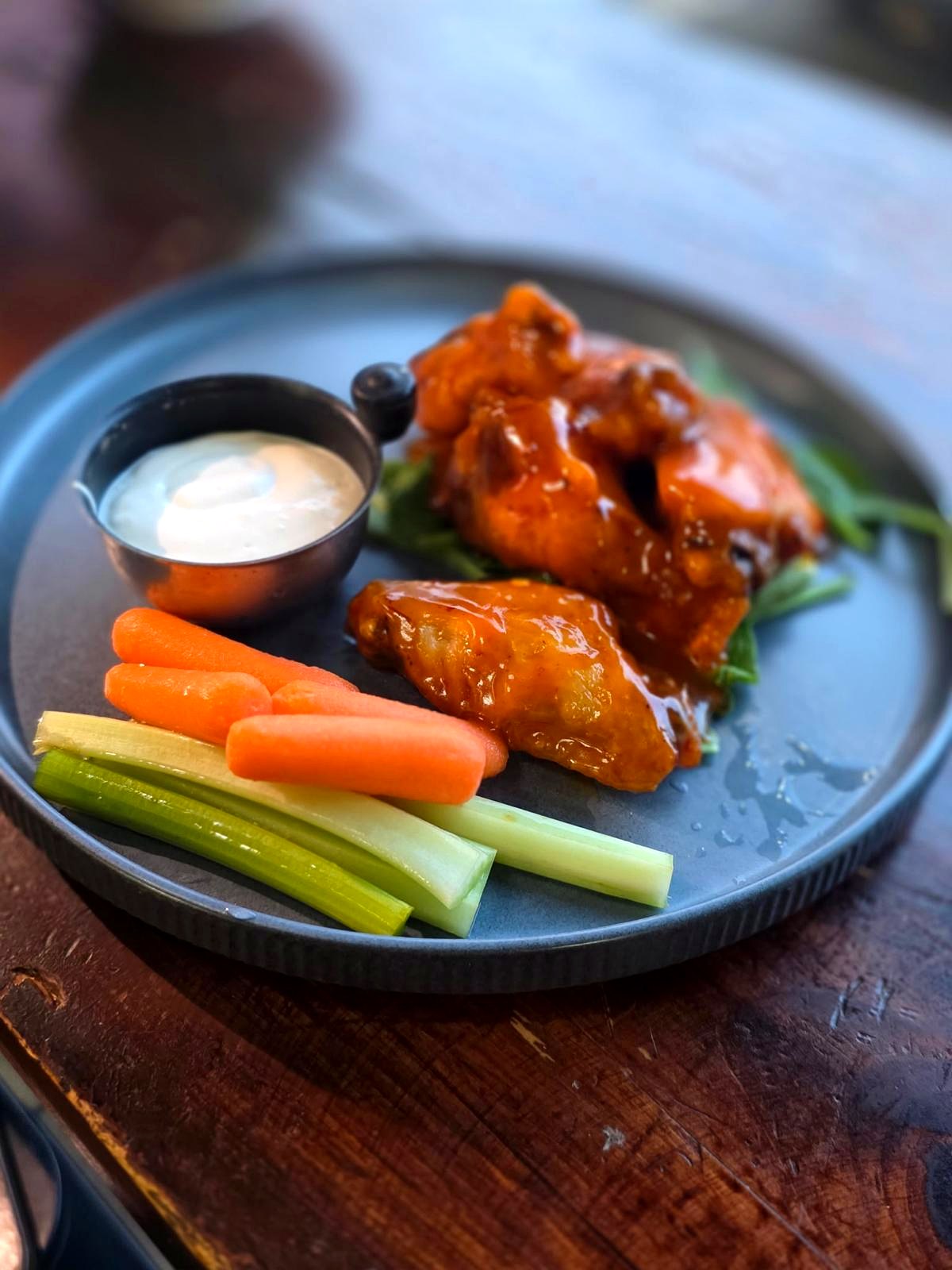 Alitas de pollo con salsa y palitos de zanahoria y apio