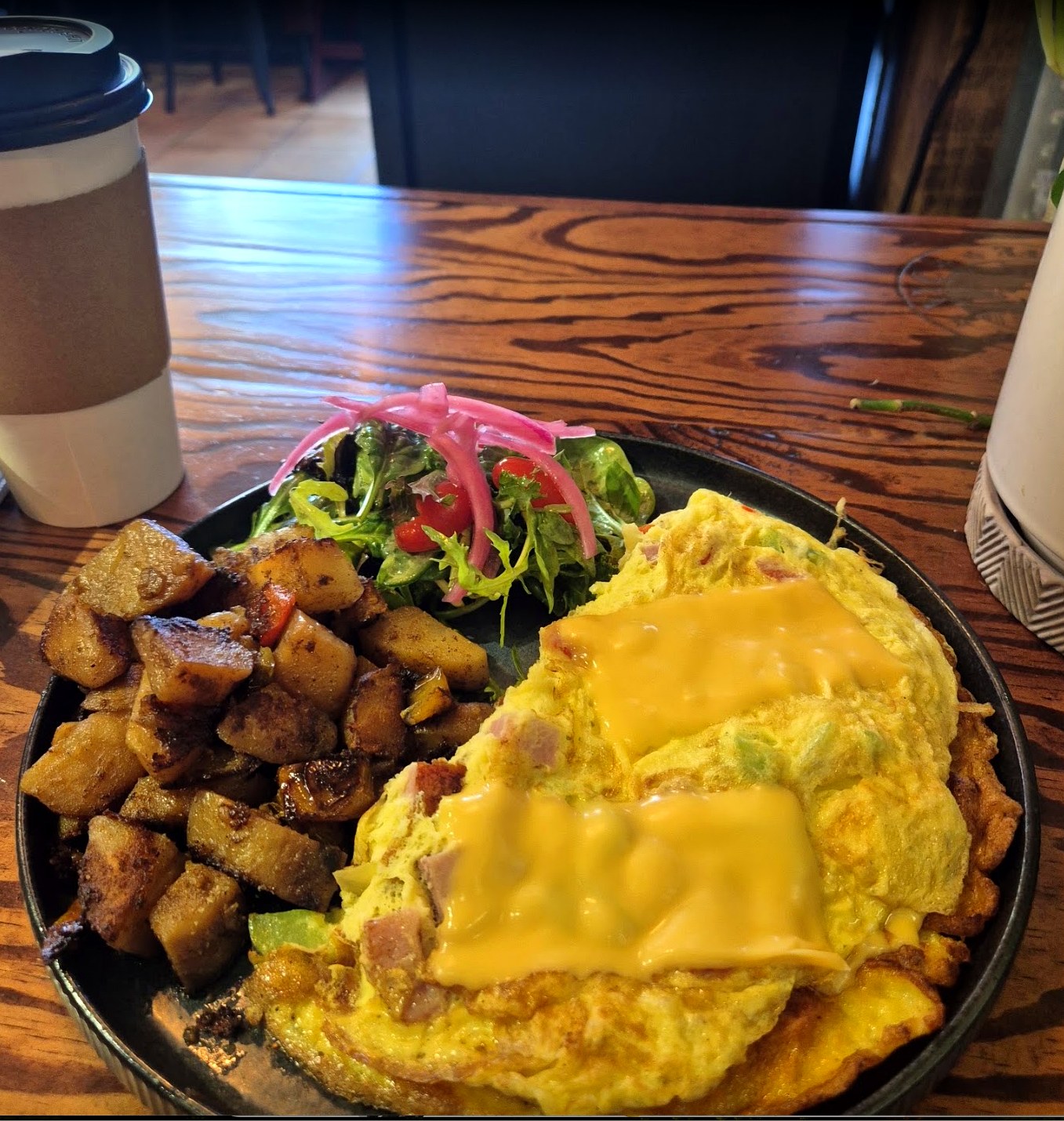 Omelette especial NYC Breakfast Caffe con queso fundido, patatas y ensalada